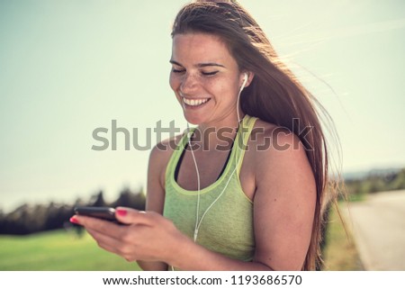 Similar – Woman with earphones listening music in smartphone