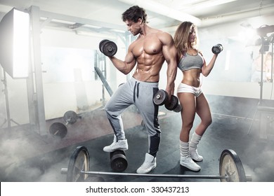 schönes sportliches Paar, das Muskeln und Training im Fitnessraum während des Fotografierens zeigt