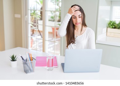Beautiful young student woman studying for university using laptop and notebook stressed with hand on head, shocked with shame and surprise face, angry and frustrated. Fear and upset for mistake.