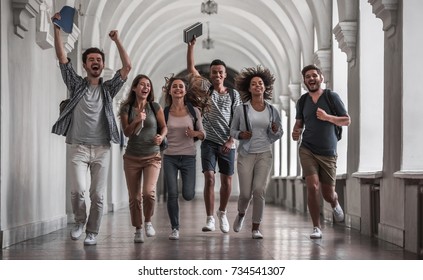 Beautiful Young Students Are Looking At Camera And Smiling While Running Through The University Hall