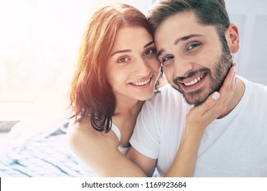 Beautiful young stylish couple in love are hugging each other and enjoying the time spent together in bedroom at home. Love concept and St. Valentines day. Relationships and family - Shutterstock ID 1169923684