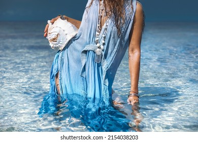 beautiful young stylish woman on in water with sea shell