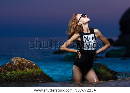 Beautiful young teen girl in the sea during fashion shoot at sunset beach