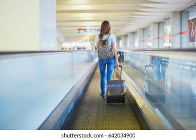 Beautiful Young Tourist Girl With Backpack And Carry On Luggage In International Airport, On Travelator