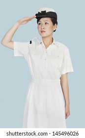 Beautiful Young US Navy Officer Saluting Over Light Blue Background