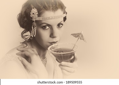 Beautiful Young Vintage 1920s Woman With Headband And Flapper Dress Drinking A Cocktail