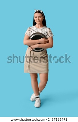 Beautiful young waitress with tray on blue background