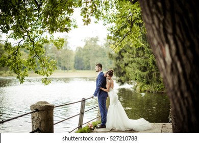 Beautiful young wedding couple, bride and groom posing on lake background. The groom and the bride on pier.