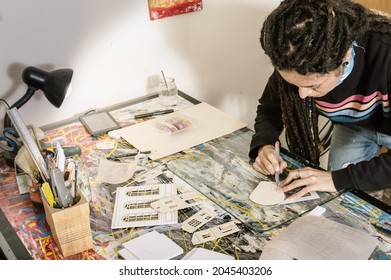 Beautiful Young White Hispanic Latin Art Director Girl With Dreadlocks In Her Design Studio, Cutting Styrofoam With Precision With An Eyelet, Making A Cinematic Model.