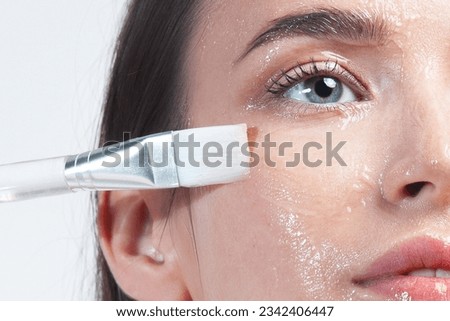 Beautiful young white woman applying cleansing gel to her facial skin using brush. Skin care, cleansing and moisturizing
