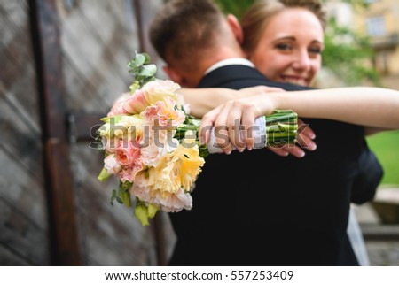 beautiful and young wife with flowers hugging her husband
