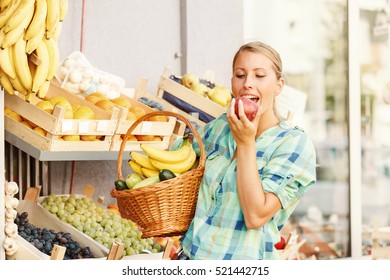 Beautiful Young Woamn Eating Apple In Grocery Store. 