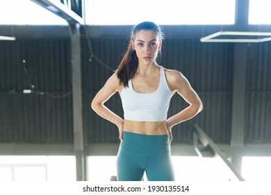 Beautiful Young Woman In Activewear Standing Inside The Gym And Making Eye Contact. Fit And Strong Woman Posing With Her Hands On The Hips