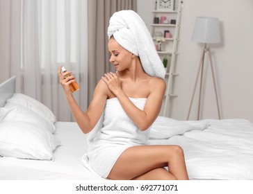 Beautiful Young Woman After Bath Applying Body Oil Onto Skin At Home