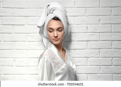 Beautiful young woman after shower on white brick wall background