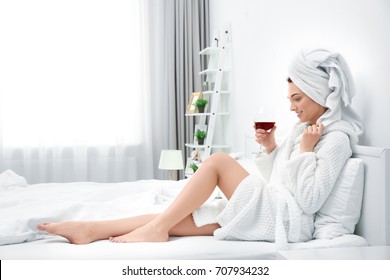 Beautiful Young Woman After Shower In Bathrobe With Glass Of Red Wine At Home