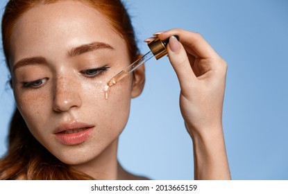 Beautiful young woman apply moisturizing facial serum isolated on blue background. Morning daily beauty luxury procedures. Skincare and rejuvenation concept, hand holding dropper with essential oil - Shutterstock ID 2013665159