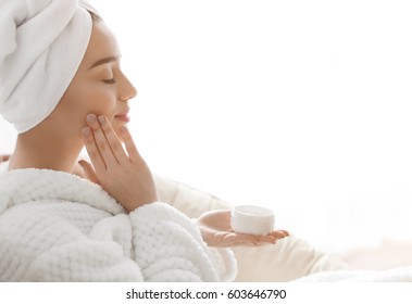 Beautiful young woman applying cream onto skin in spa salon - Powered by Shutterstock