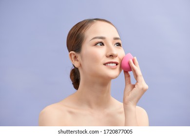 Beautiful Young Woman Applying Makeup Using Beauty Blender Sponge.