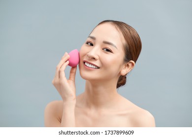 Beautiful Young Woman Applying Makeup Using Beauty Blender Sponge.