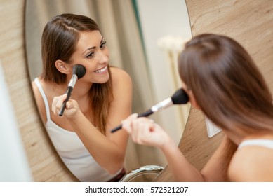 Beautiful Young Woman Applying Makeup In Front Of Her Bathroom Mirror. Selective Focus.