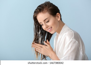 Beautiful Young Woman Applying Mousse On Her Hair After Washing Against Color Background