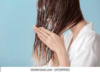 Beautiful Young Woman Applying Mousse On Her Hair After Washing Against Color Background