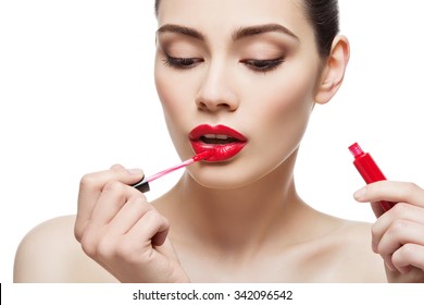 Beautiful young woman applying red lipgloss with applicator. Isolated over white background. Copy space.