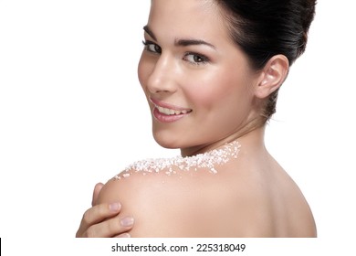 Beautiful young woman applying scrub treatment on the skin on white