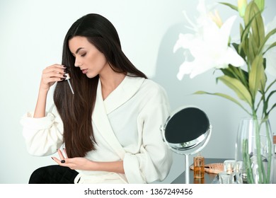 Beautiful Young Woman Applying Serum Onto Her Healthy Long Hair At Home