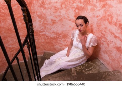 Beautiful Young Woman In Authentic Regency Gown Posing On Spiral Antique Staircase