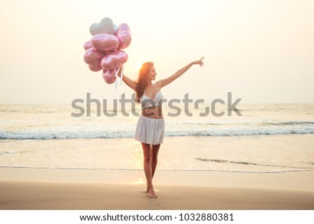 beautiful and young woman with balloons points to the sea