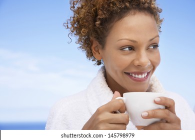 Beautiful young woman in bathrobe having coffee outdoors - Powered by Shutterstock