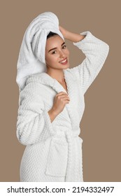 Beautiful young woman in bathrobe on brown background