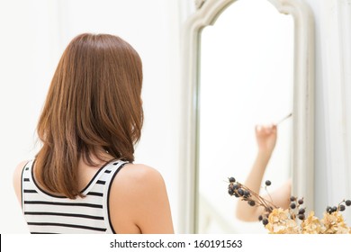Beautiful young woman in bathroom looking at herself in mirror