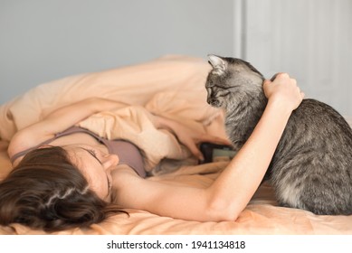 Beautiful Young Woman In Bed At Home With Tabby Cat