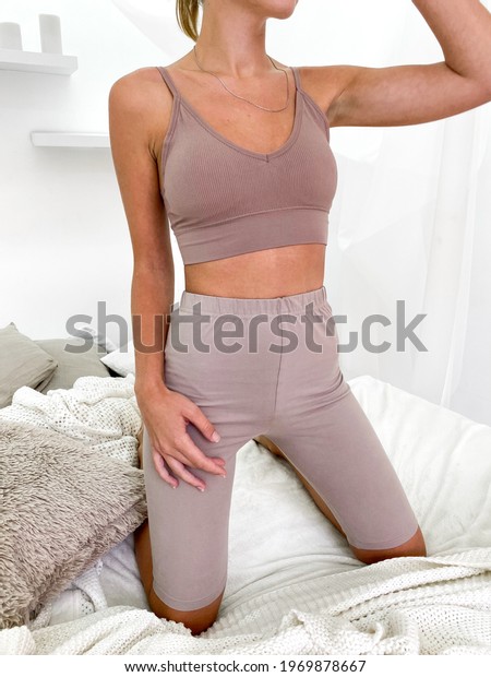 Beautiful young woman in bed wearing sports bra\
and knee length\
leggings