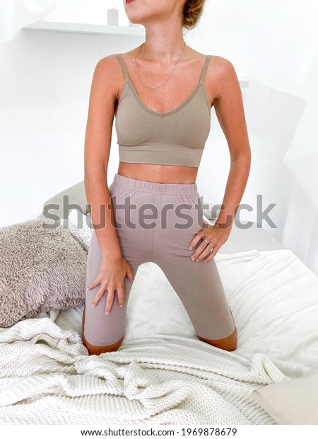 Beautiful young woman in bed wearing sports bra\
and knee length\
leggings