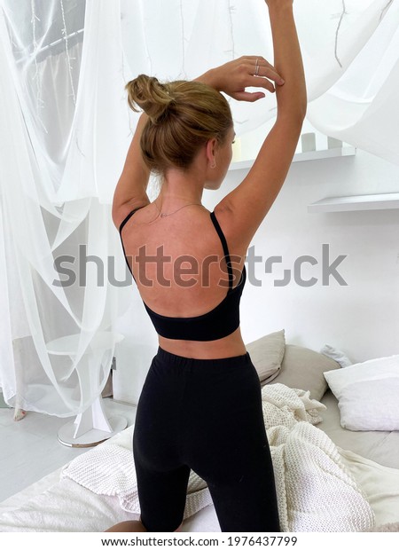Beautiful young woman in bed wearing black\
sports bra and knee length\
leggings