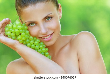 Beautiful young woman bites off from grape bunches, against summer green park. - Powered by Shutterstock