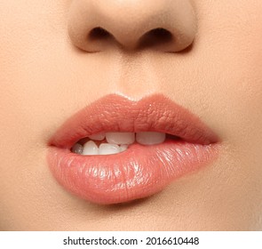 Beautiful young woman biting lip on grey background, closeup