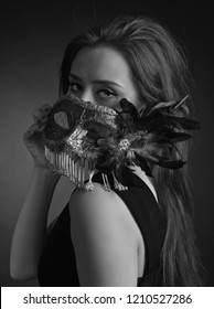 Beautiful young woman in black dress with carnival mask. Black and White Fashion photo.