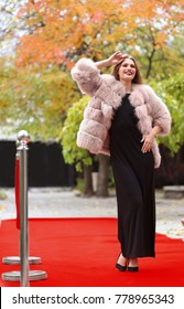 Beautiful Young Woman In Black Dress And Fur Coat On Red Carpet, Outdoors