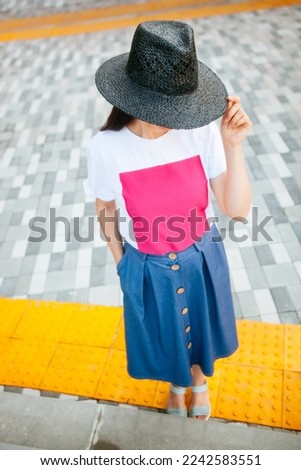 Beautiful young woman in black hat on the street, vertical card with copy space