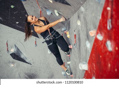 Beautiful Young Woman In Black Outfit Climbing On Practical Wall In Gym, Bouldering, Extreme Sport, Rock-climbing Concept