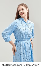 A beautiful young woman with blond hair, wearing a light blue blouse, smiles joyfully. Happy people. Women's beauty and health. Gray studio background.