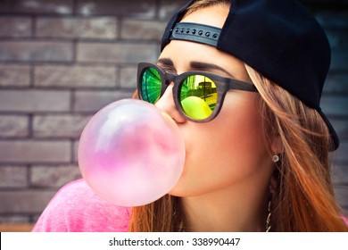 Beautiful young woman blowing a bubble gum balloon