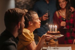 Beautiful Young Woman Blowing Candles On Birthday Cake.