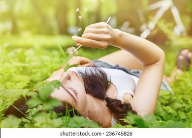 Beautiful young woman blowing a dandelion - Shutterstock ID 236745826