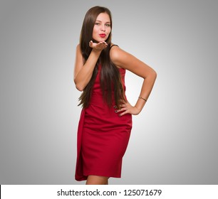Beautiful Young Woman Blowing A Kiss against a grey background